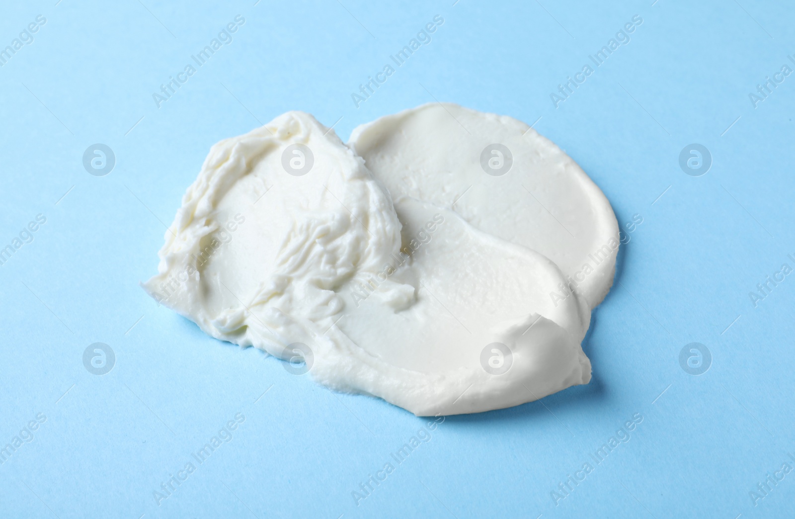 Photo of Smear of delicious cream cheese on light blue background