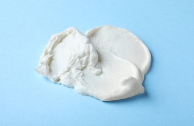 Photo of Smear of delicious cream cheese on light blue background