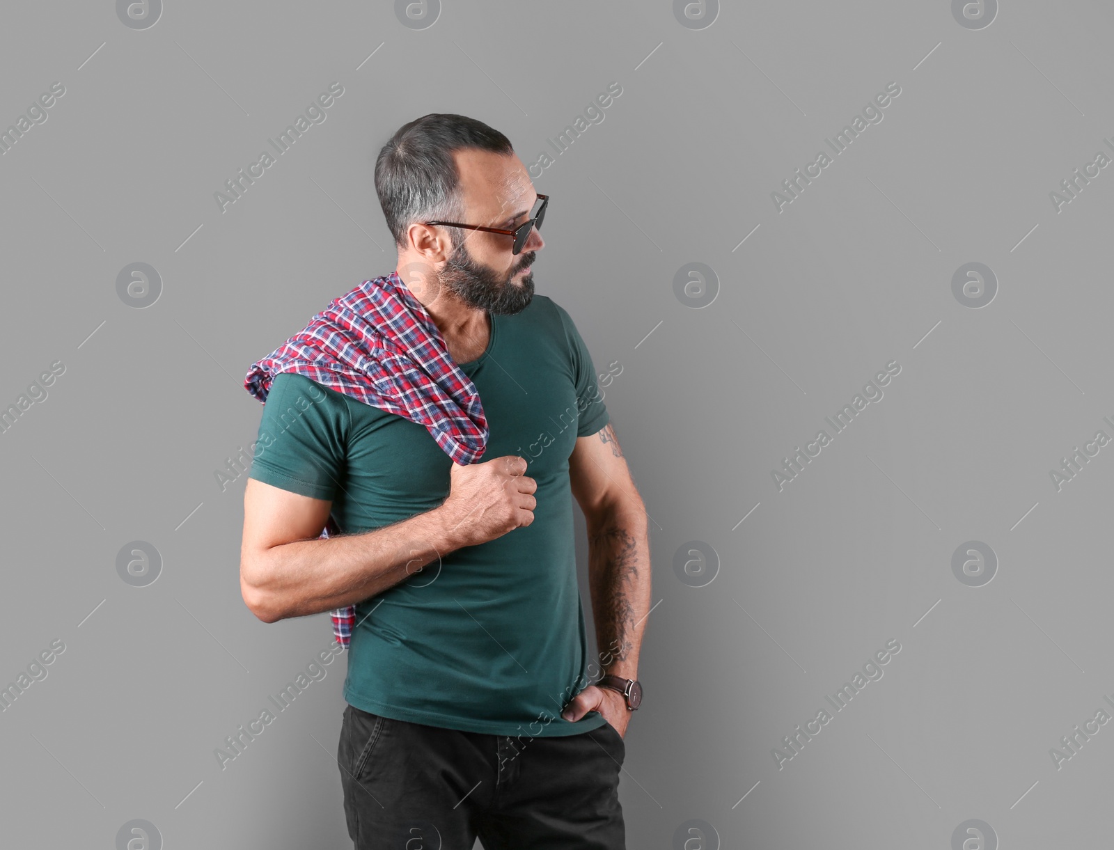 Photo of Portrait of handsome tattooed man on grey background