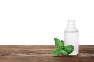 Bottle of essential oil and mint on wooden table against white background