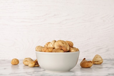 Photo of Bowl with dried figs on marble table, space for text. Healthy fruit