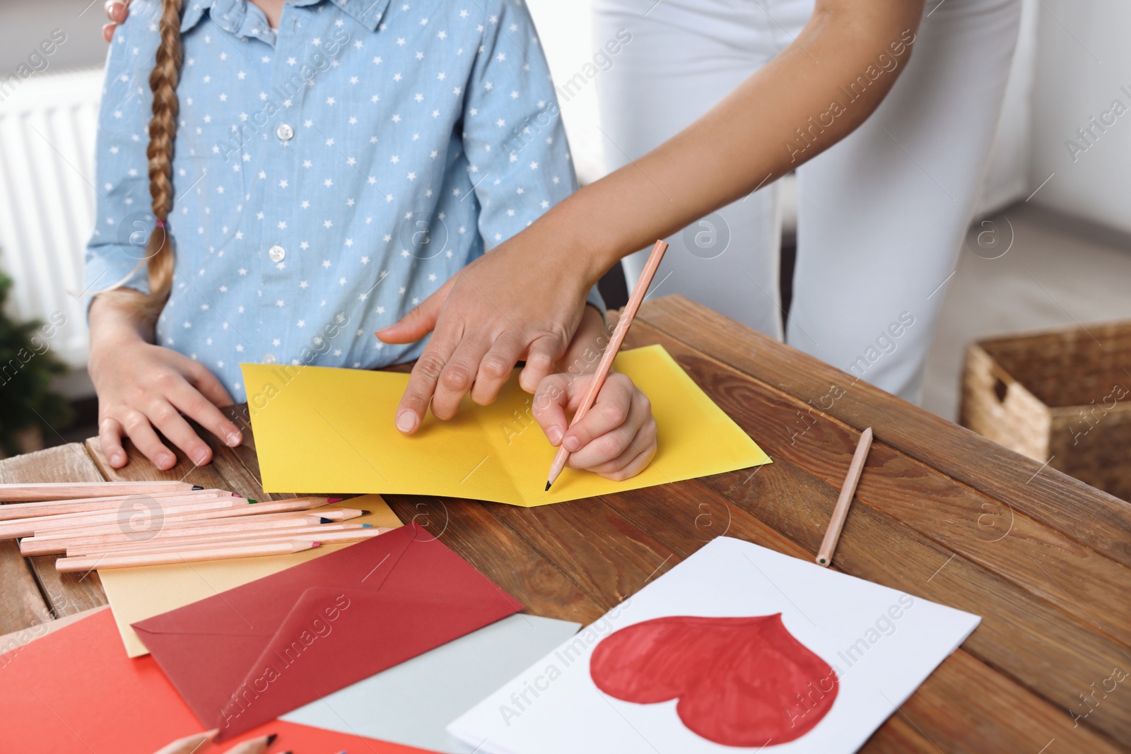 Photo of Little girl with her mother making beautiful greeting card at home, closeup