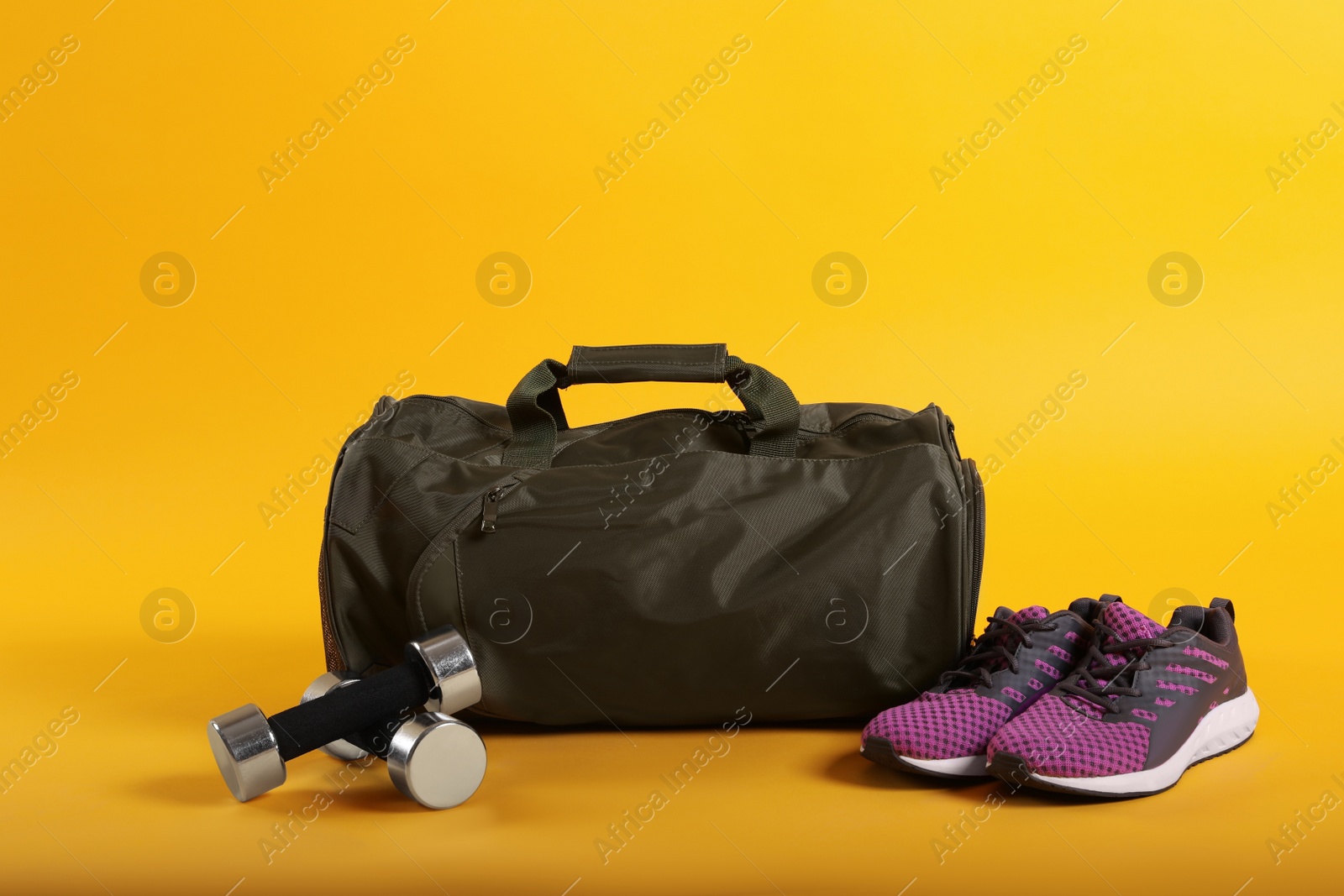 Photo of Sports bag and gym equipment on yellow background