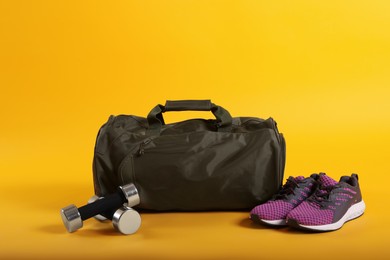 Photo of Sports bag and gym equipment on yellow background