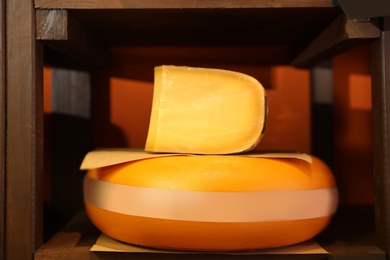 Photo of Delicious cheese on rack shelf in store. Dairy product