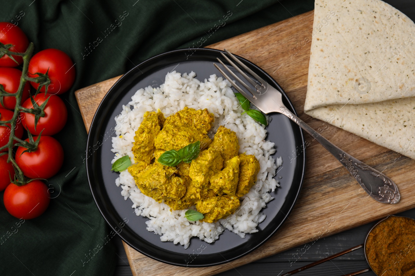 Photo of Delicious rice with chicken curry and products on table, flat lay