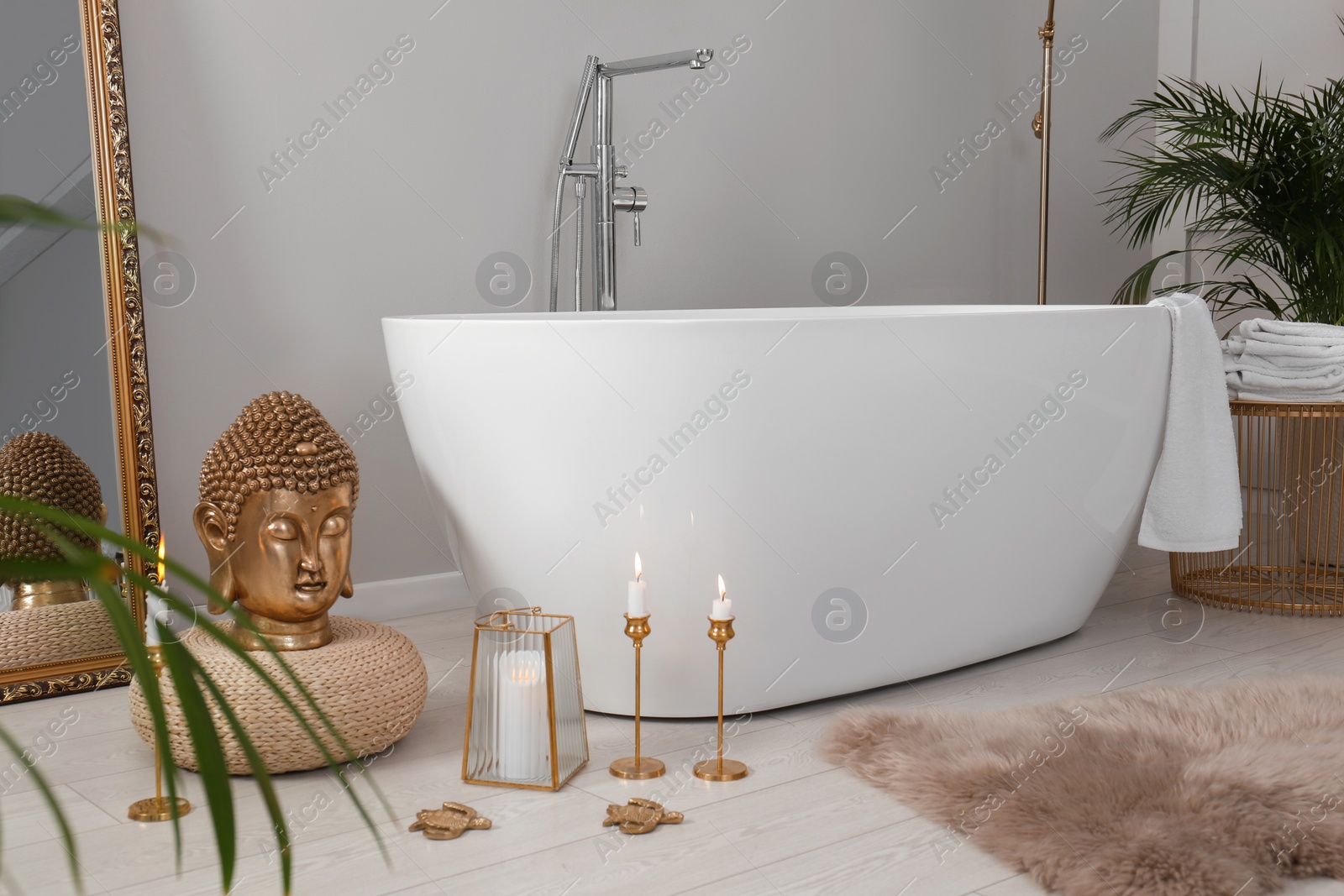 Photo of Bathroom interior with golden Buddha sculpture and modern white tub