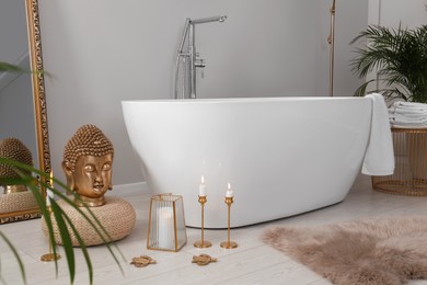 Photo of Bathroom interior with golden Buddha sculpture and modern white tub