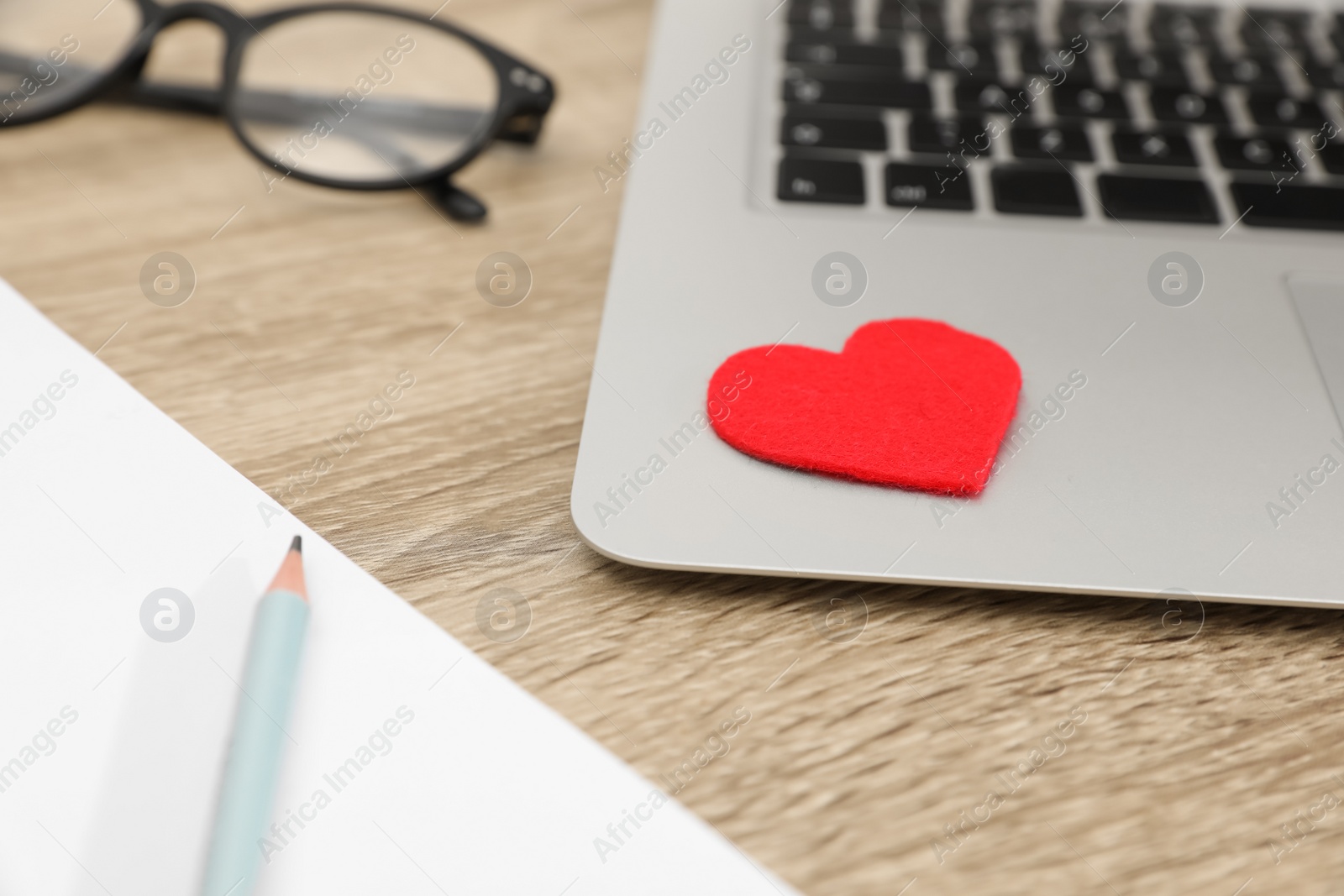 Photo of Red heart on laptop in office, closeup. Valentine's day celebration