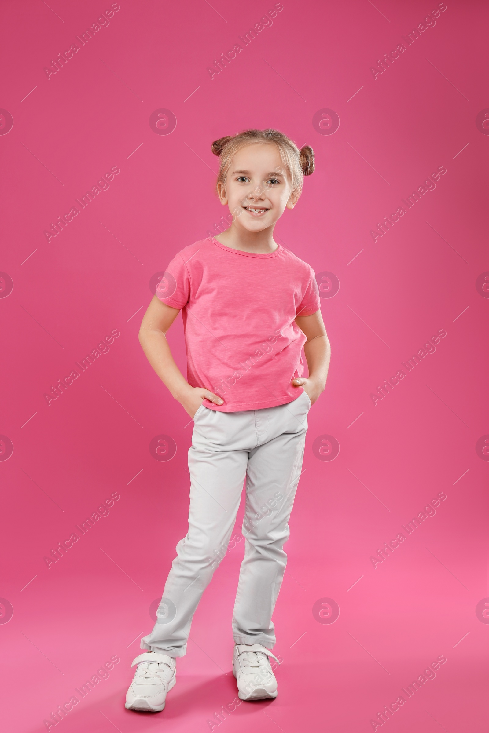 Photo of Cute little girl posing on pink background