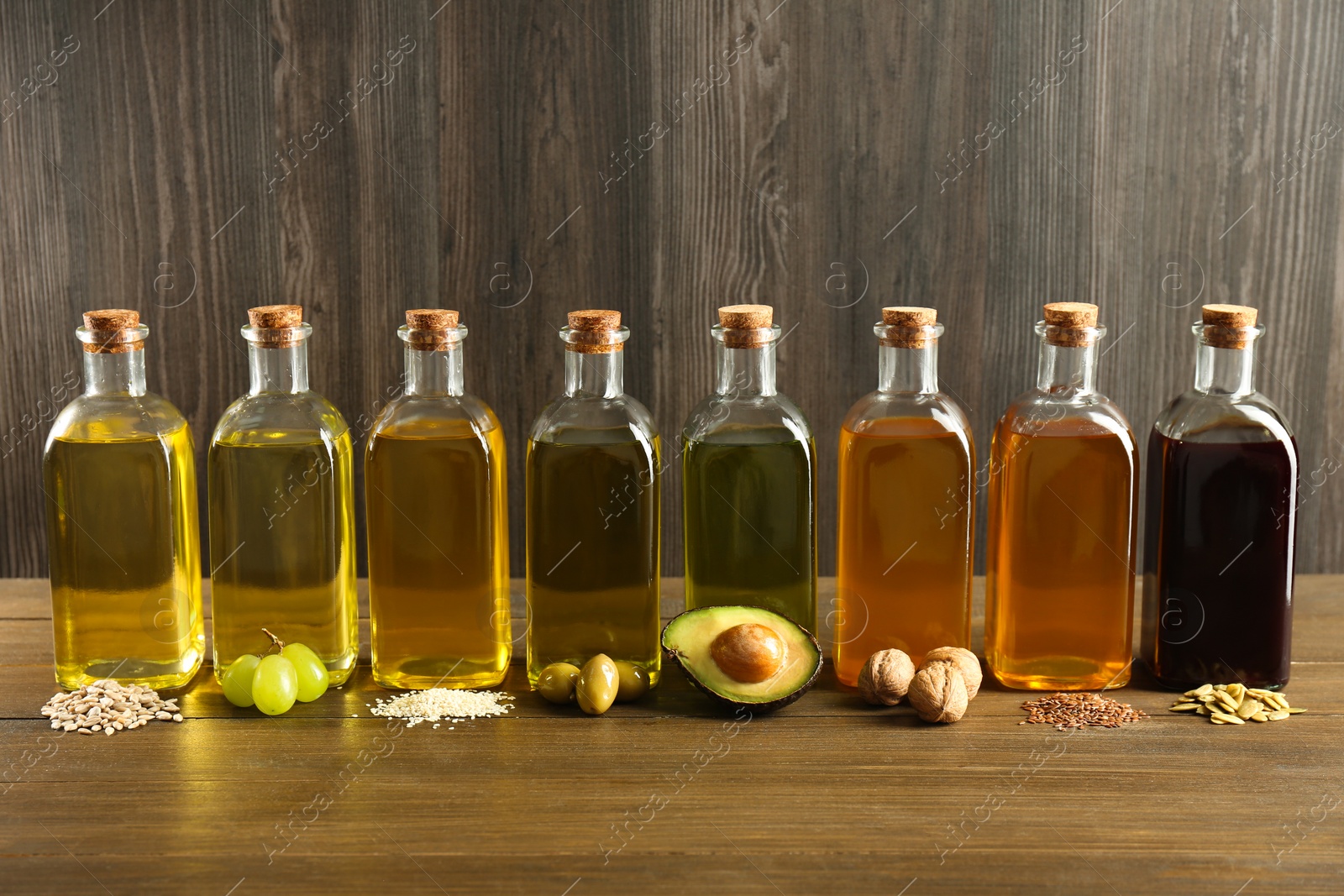 Photo of Vegetable fats. Different oils in glass bottles and ingredients on wooden table