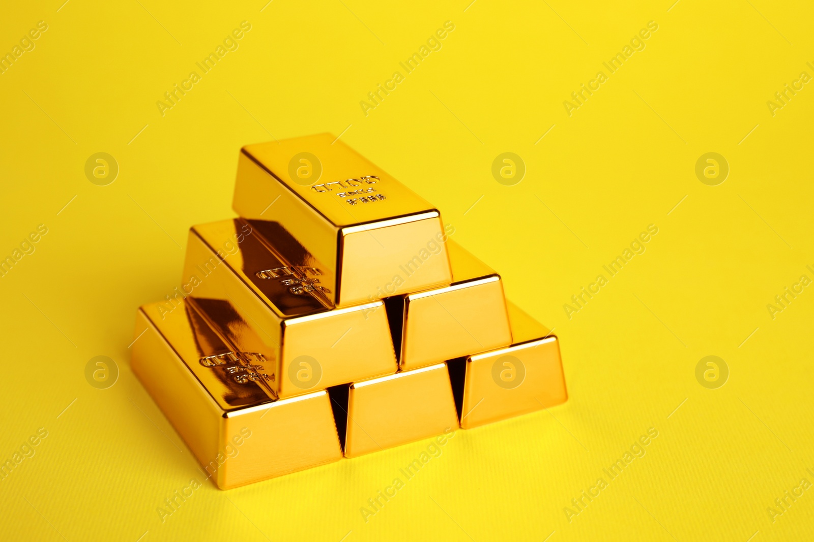 Photo of Stack of shiny gold bars on yellow background