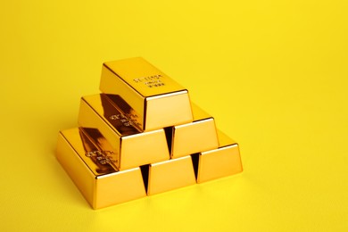 Photo of Stack of shiny gold bars on yellow background