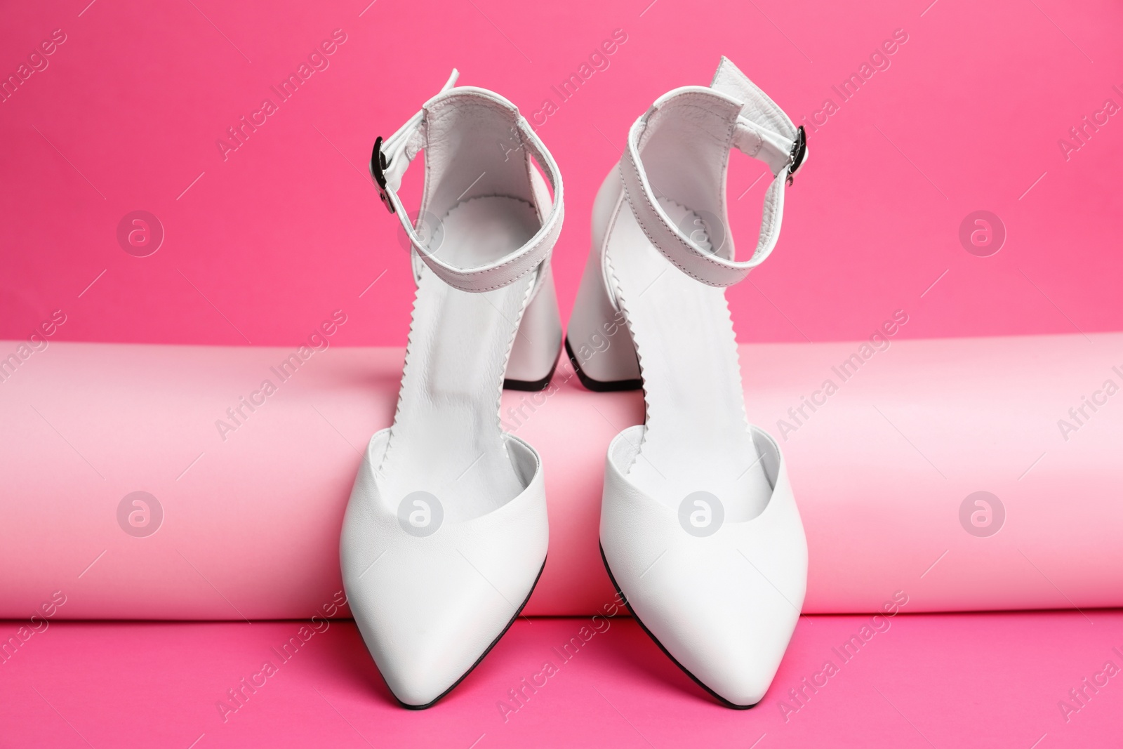 Photo of Stylish white female shoes on pink background