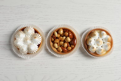 Photo of Different tartlets on white wooden table, flat lay. Tasty dessert