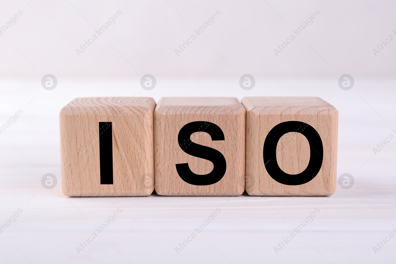 Photo of International Organization for Standardization. Wooden cubes with abbreviation ISO on white table, closeup