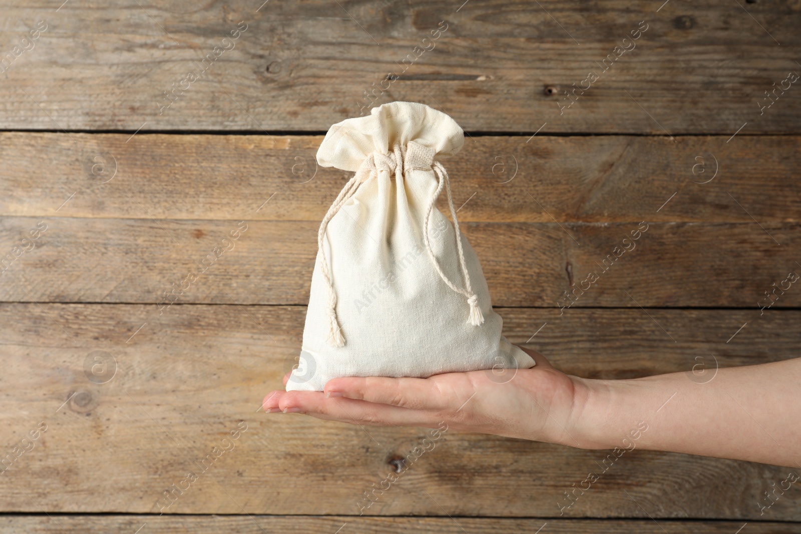 Photo of Woman holding full cotton eco bag on wooden background, closeup