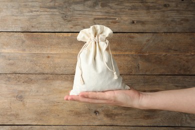 Photo of Woman holding full cotton eco bag on wooden background, closeup