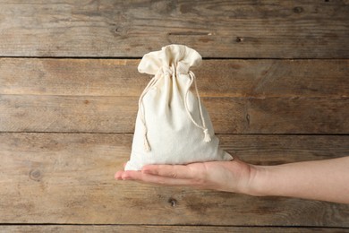 Woman holding full cotton eco bag on wooden background, closeup