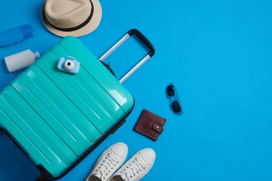 Photo of Flat lay composition with suitcase and travel accessories on light blue background, space for text. Summer vacation