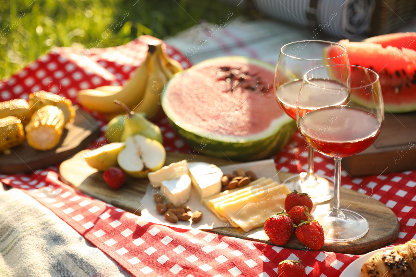 Photo of Picnic blanket with delicious food and drinks outdoors on sunny day, closeup