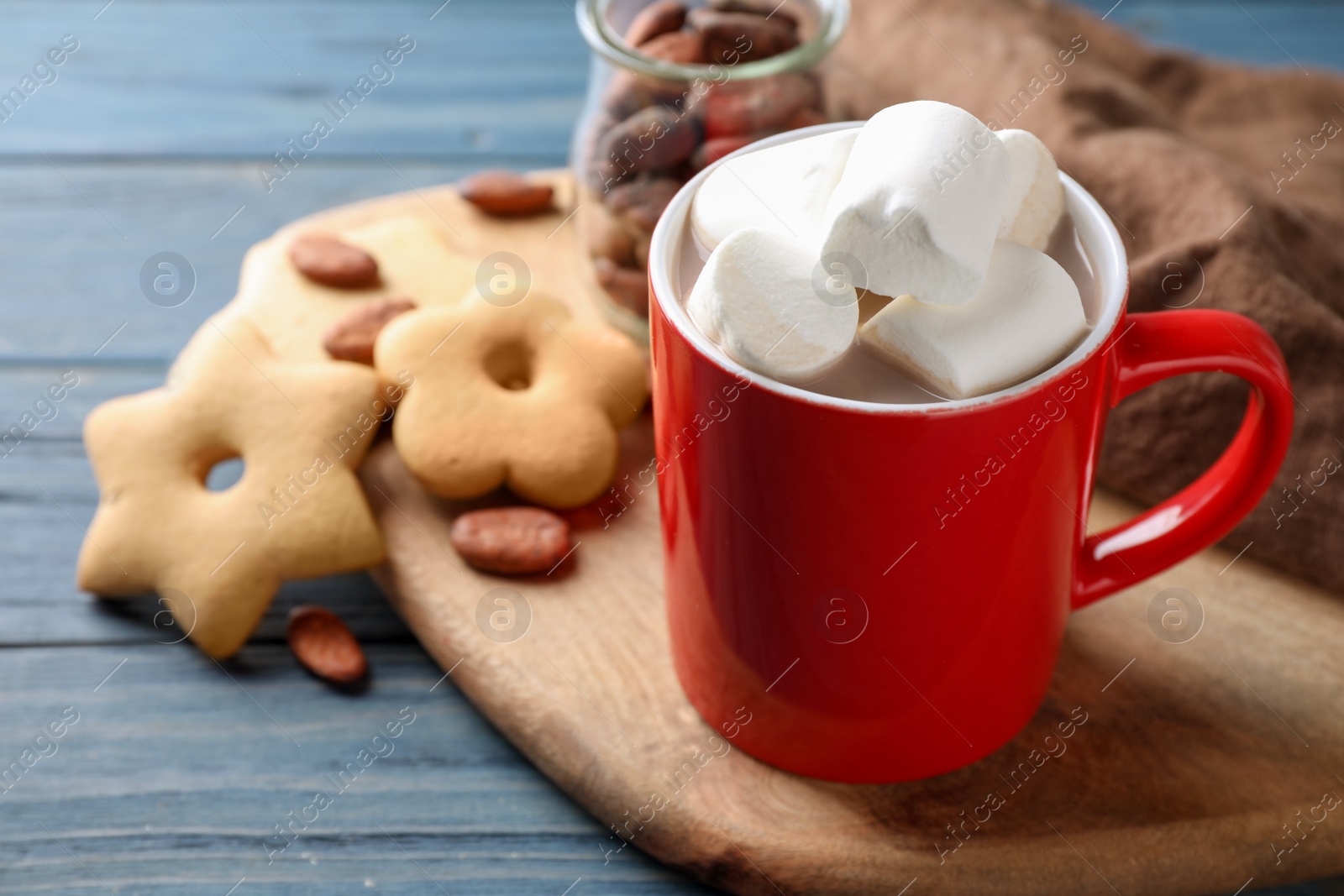 Photo of Composition of tasty cocoa with marshmallows in cup on blue wooden table. Space for text