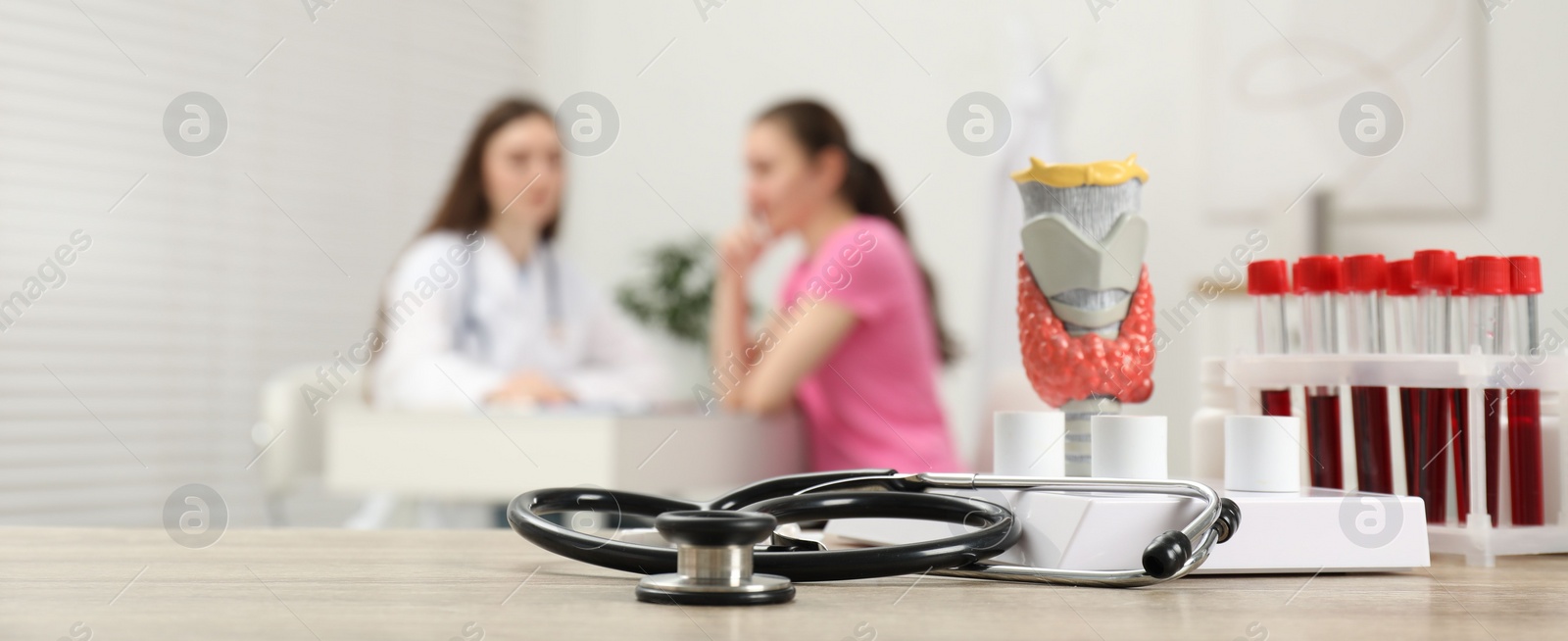 Photo of Endocrinologist examining patient at clinic, focus on stethoscope and model of thyroid gland. Banner design