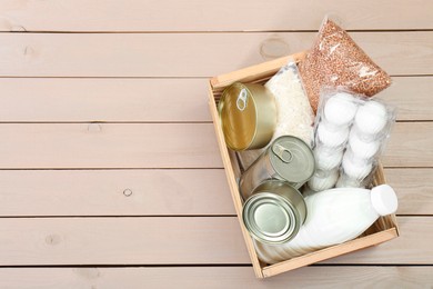 Donation box with food products on wooden table, top view. Space for text