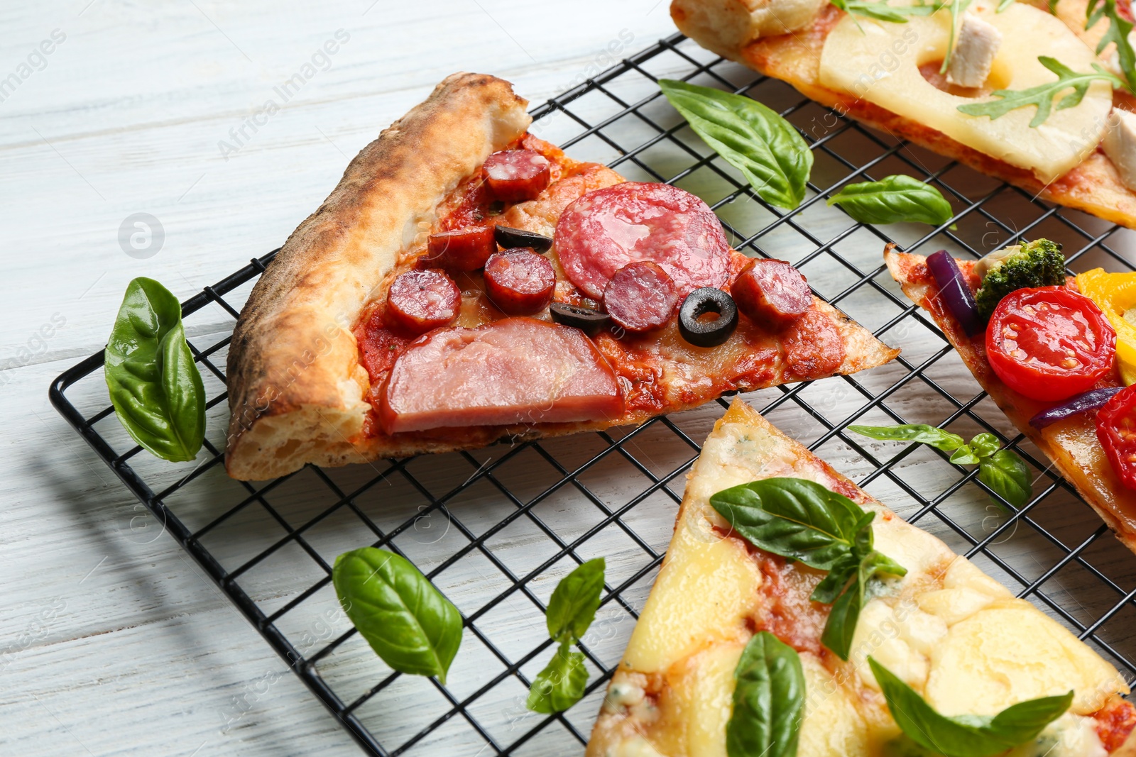 Photo of Slices of different delicious pizzas on white wooden table, closeup