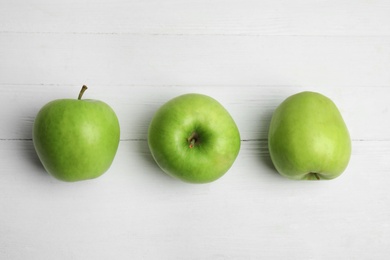 Ripe green apples on white wooden table, flat lay