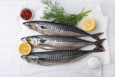 Photo of Tasty salted mackerels, spices and cut lemons on white table, flat lay