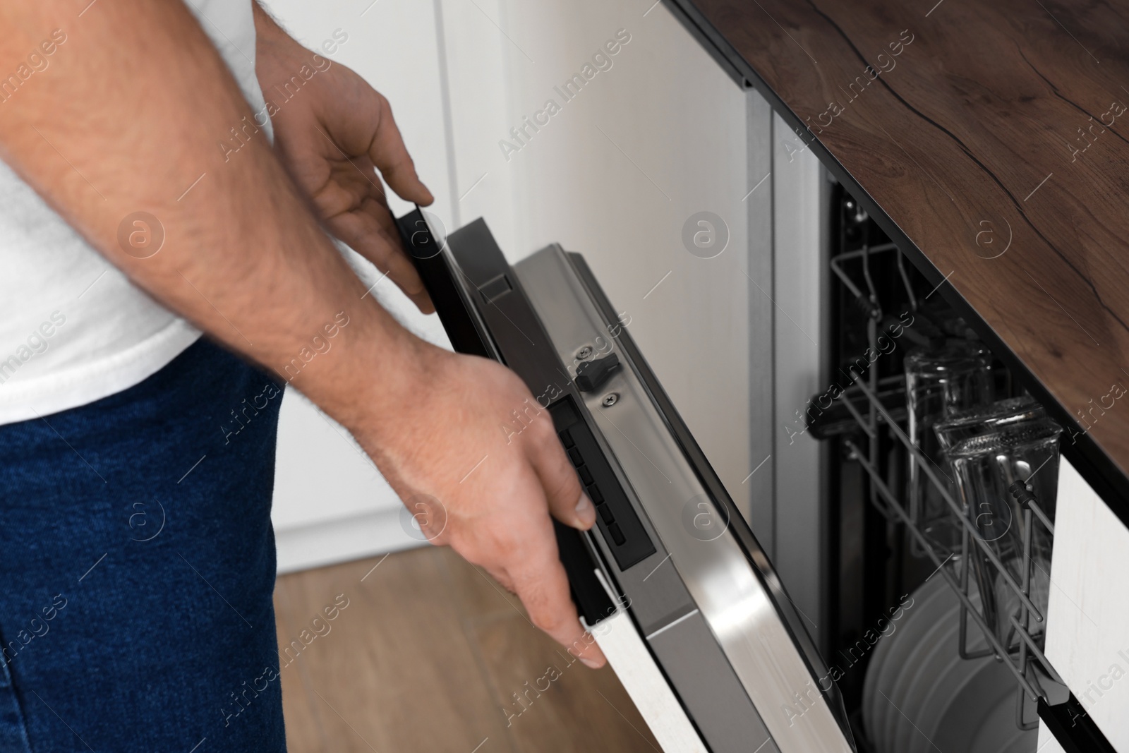 Photo of Man opening dishwasher's door in kitchen, closeup