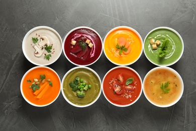 Photo of Various cream soups in bowls on grey background, top view