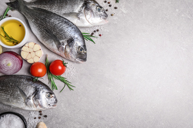 Flat lay composition with dorada fish on light grey table, space for text