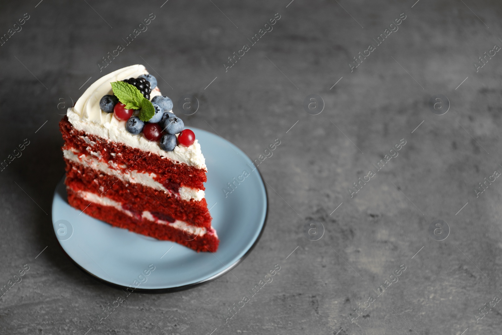 Photo of Plate with piece of delicious homemade red velvet cake and space for text on table