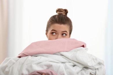 Woman holding pile of dirty laundry indoors