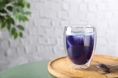 Delicious blue matcha tea with ice cubes on table, space for text