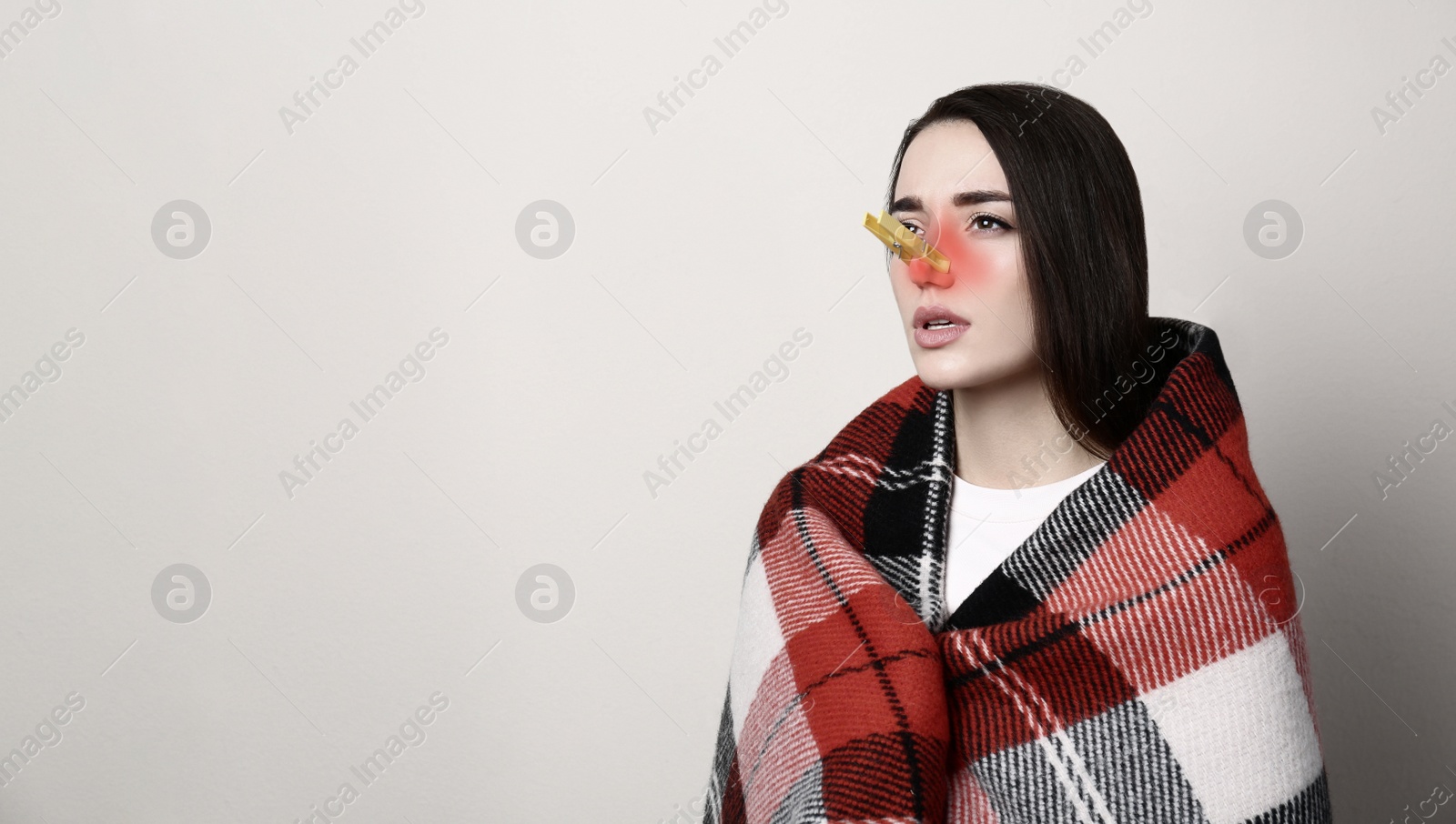 Image of Young woman with clothespin on light background, space for text. Runny nose concept