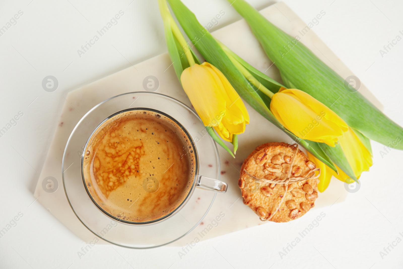 Photo of Aromatic morning coffee, cookies and beautiful flowers on white table, flat lay