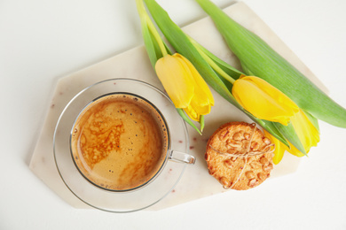 Aromatic morning coffee, cookies and beautiful flowers on white table, flat lay