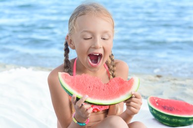 Cute little girl eating juicy watermelon on beach