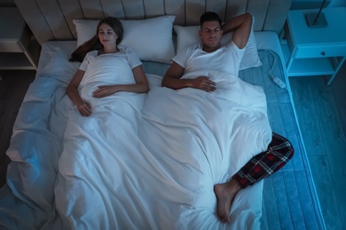 Photo of Couple sleeping on electric heating pad in bed at night, above view