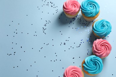 Photo of Delicious cupcakes with bright cream and confetti on light blue background, flat lay. Space for text