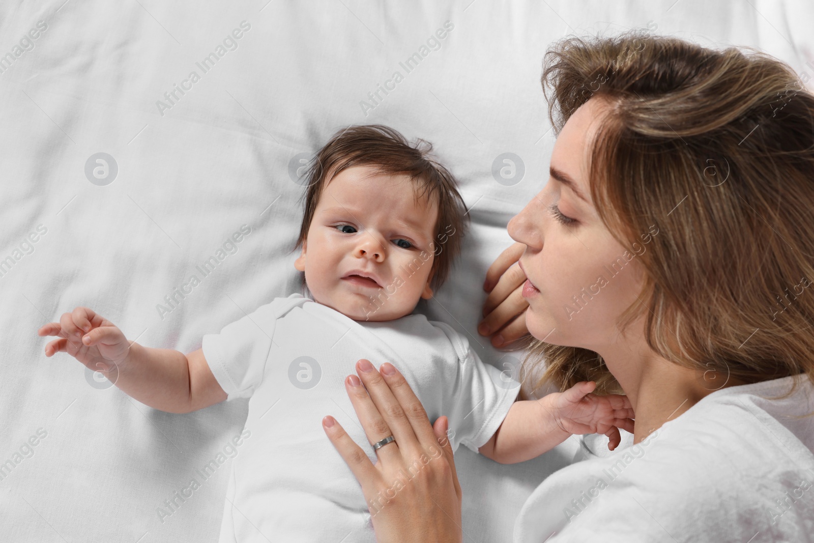 Photo of Mother calming crying daughter on bed, top view