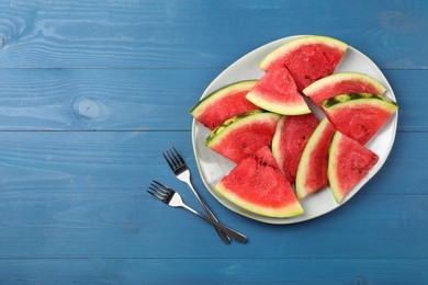 Photo of Plate with slices of juicy watermelon on blue wooden table, top view. Space for text