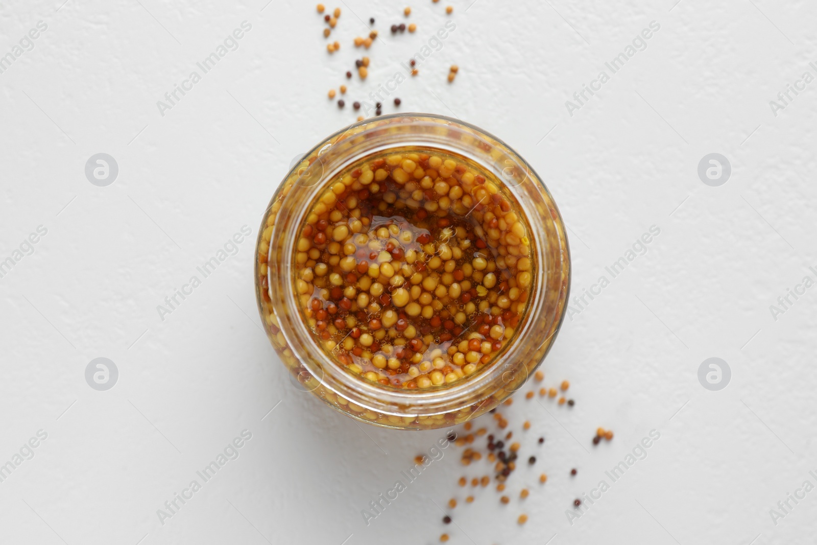 Photo of Fresh whole grain mustard in bowl and dry seeds on white table, flat lay