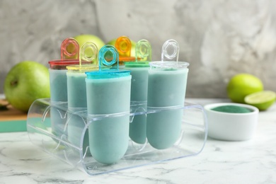 Photo of Spirulina popsicles in ice cream mold on marble table