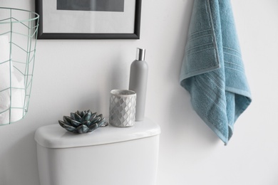 Decor elements, necessities and toilet bowl near white wall. Bathroom interior