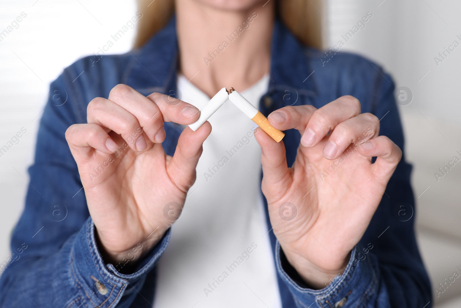 Photo of Woman breaking cigarette on light background, selective focus. Quitting smoking concept