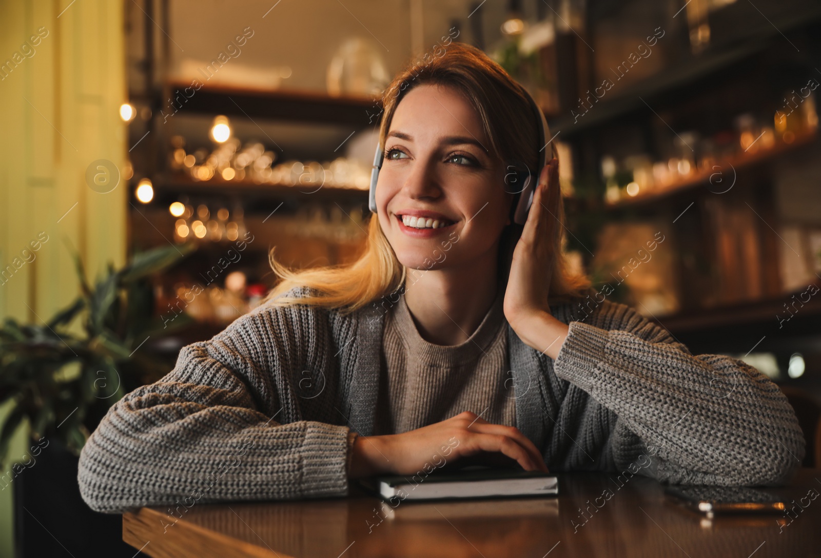 Photo of Woman listening to audiobook at table in cafe